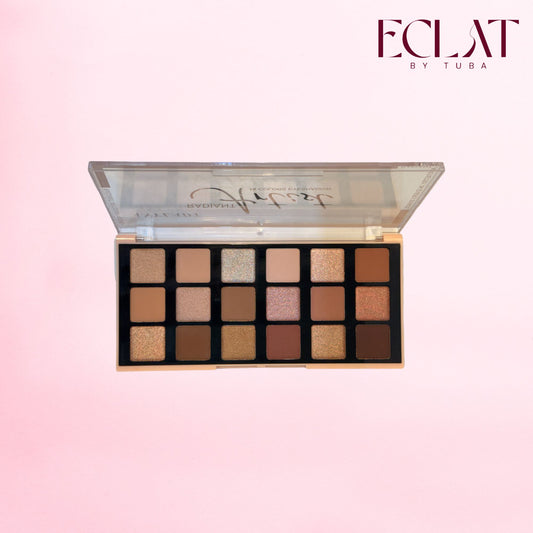 An open eyeshadow palette with 16 square pans in neutral shades, shown against a soft pink gradient background. The brand name 'ECLAT BY TUBA' is visible in the top right corner.