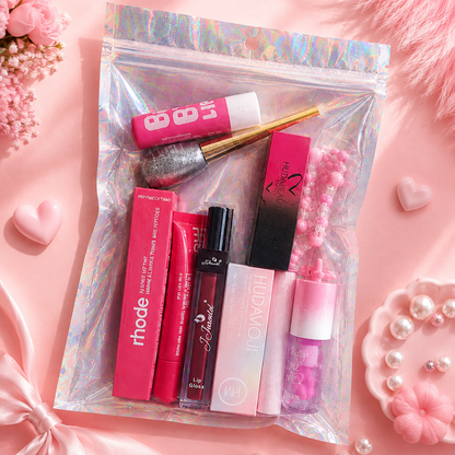 A clear holographic zippered pouch filled with pink and red beauty products, including lip gloss, a brush, and a black-and-pink box, arranged on a soft pink background with decorative hearts, pearls, and flowers. The brand name ECLAT BY TUBA appears in the top left, and social handle icons appear along the bottom.